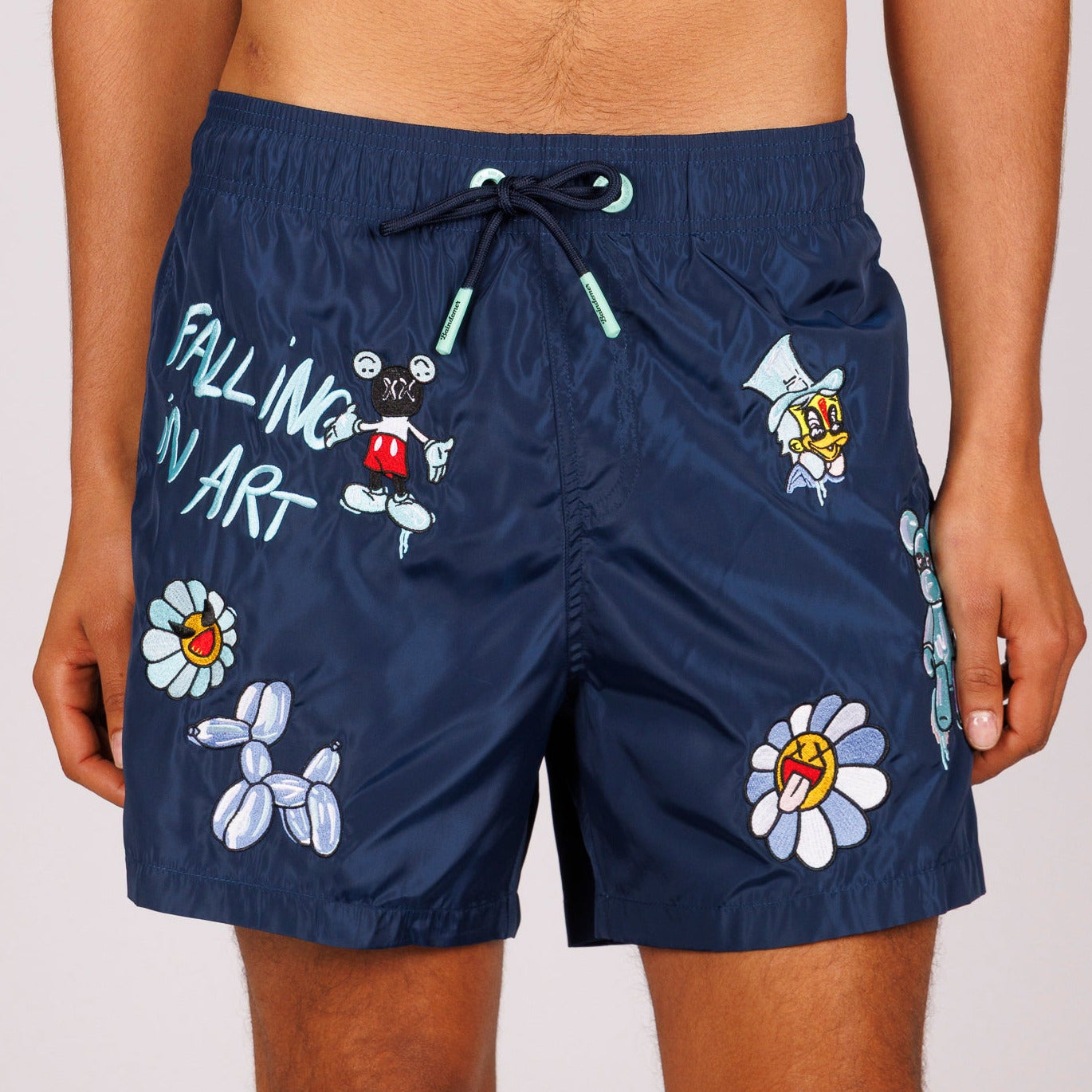 Navy blue swim shorts front view with illustrated graphic and “Falling in art” text