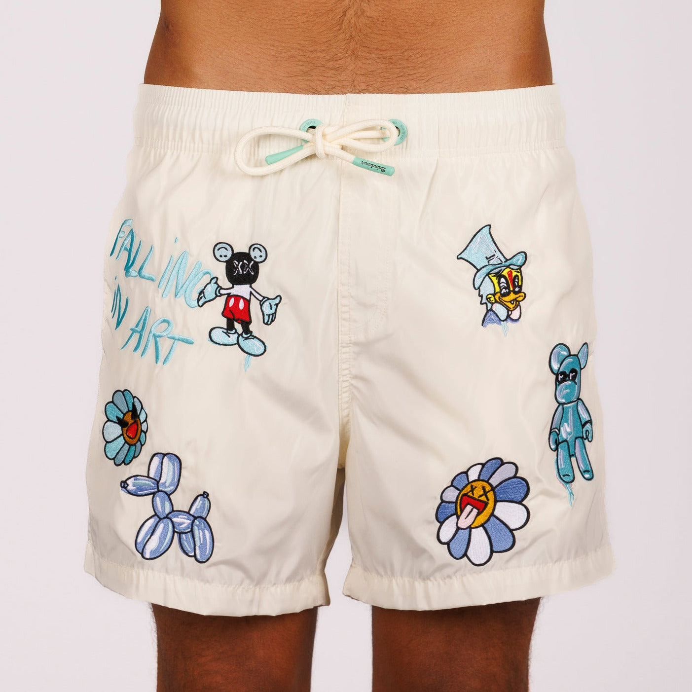 Off-white swim shorts front view with illustrated graphic and “Falling in art” text