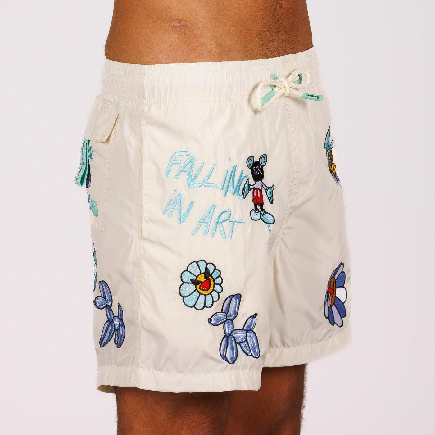 Off-white swim shorts side view with illustrated graphic and “Falling in art” text