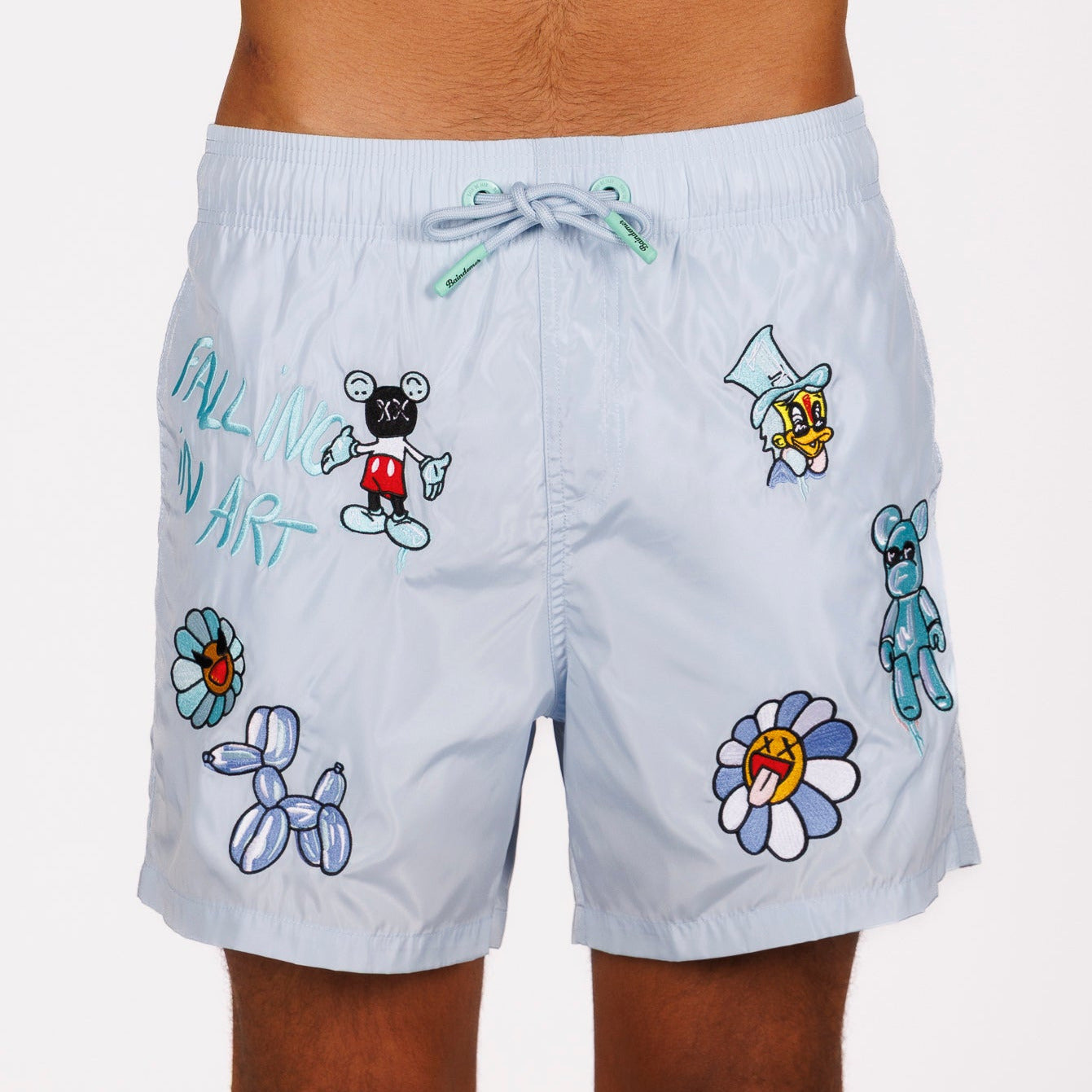 Light blue swim shorts front view with illustrated graphic and “Falling in art” text