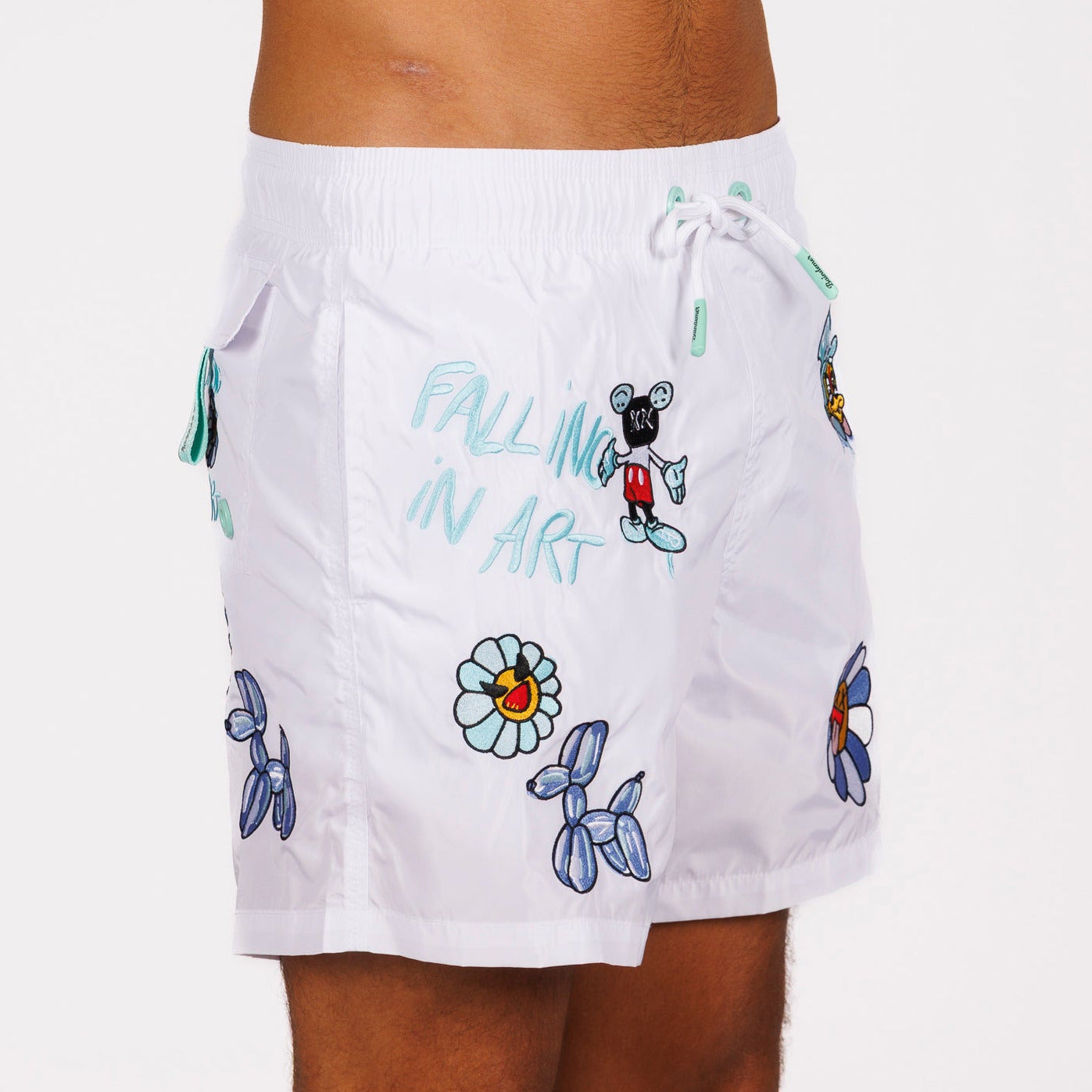 White swim shorts side view with illustrated graphic and “Falling in art” text