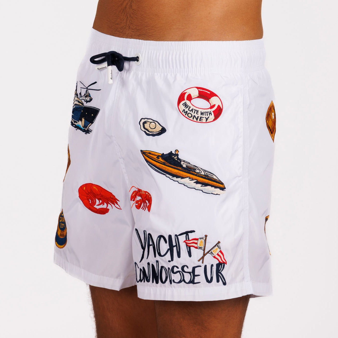 White swim shorts side view with illustrated graphic and “Yacht connoisseur” text