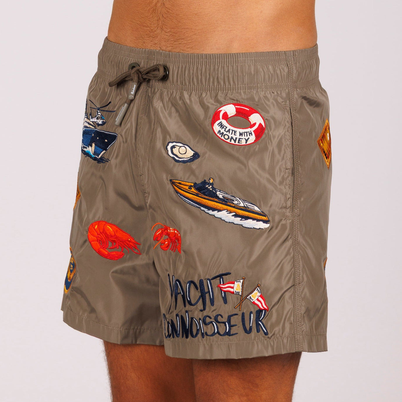 Khaki swim shorts side view with illustrated graphic and “Yacht connoisseur” text