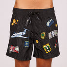 Black swim shorts front view with illustrated graphic and “Taxes optimized” text