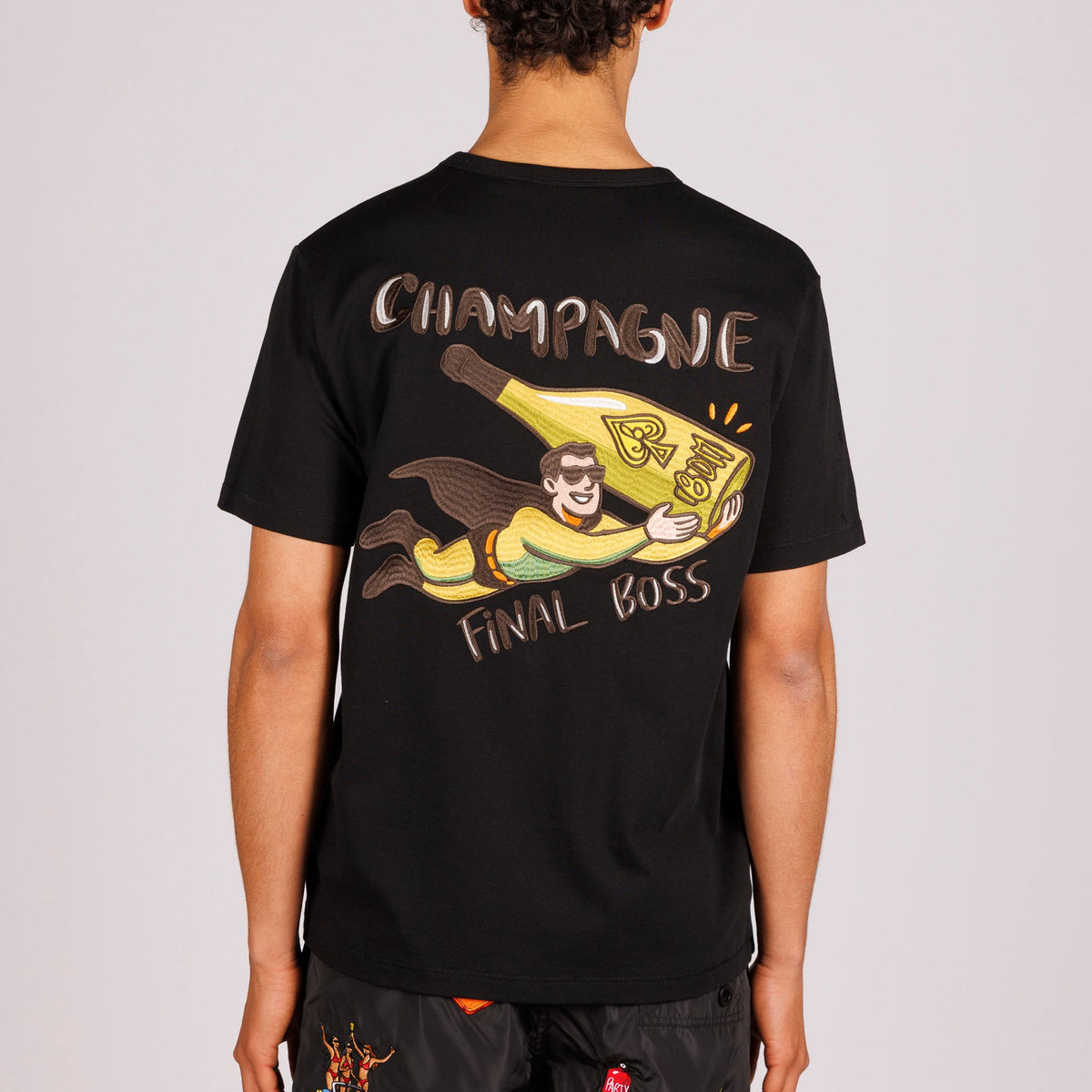 Black T-shirt back view with illustrated graphic and “Champagne final boss” text