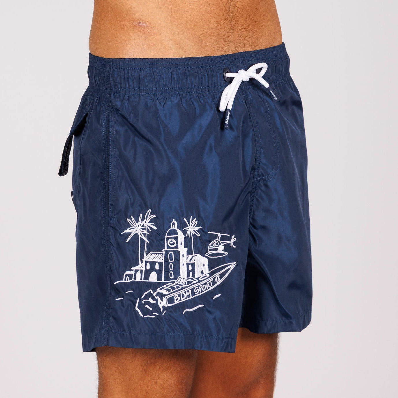 Navy blue swim shorts side view with illustrated graphic and “BDM Sport 18” text
